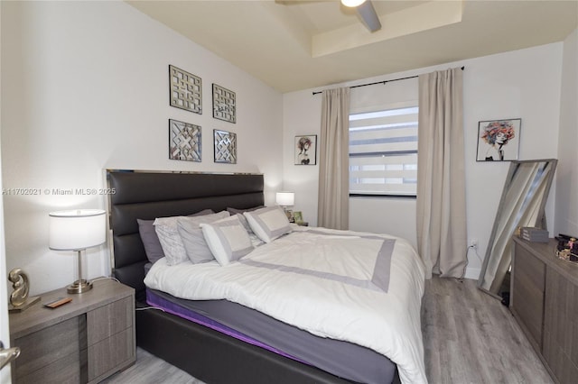 bedroom featuring a tray ceiling, ceiling fan, and light hardwood / wood-style flooring