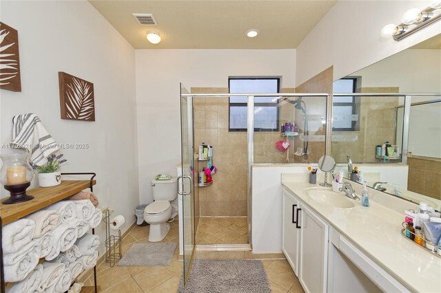 bathroom featuring tile patterned floors, vanity, a shower with shower door, and toilet