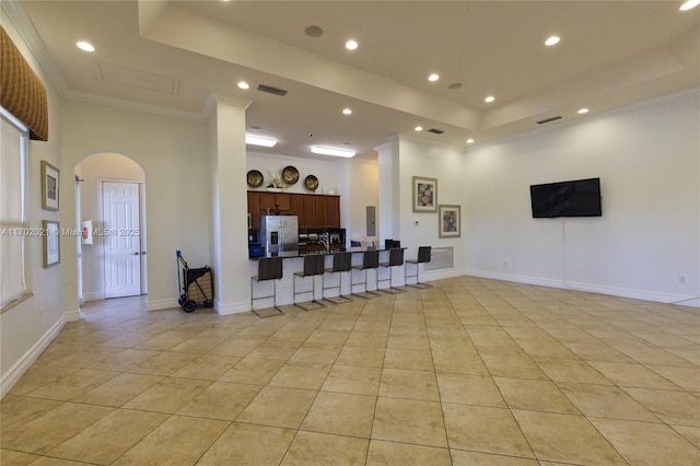 tiled living room with a raised ceiling, a towering ceiling, and crown molding