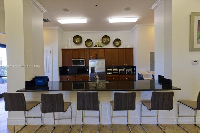 kitchen featuring kitchen peninsula, a breakfast bar, light tile patterned floors, and stainless steel appliances