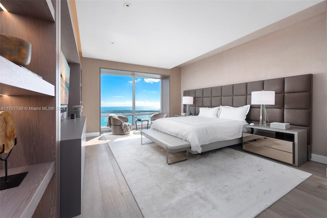 bedroom with hardwood / wood-style floors and a water view