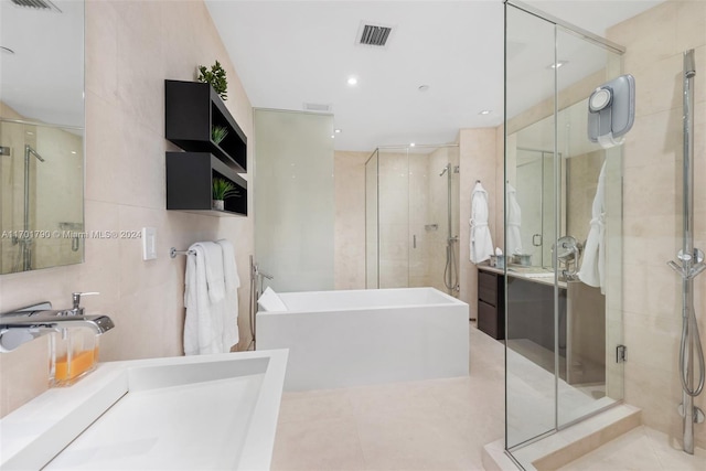 bathroom featuring tile patterned flooring, vanity, tile walls, and independent shower and bath