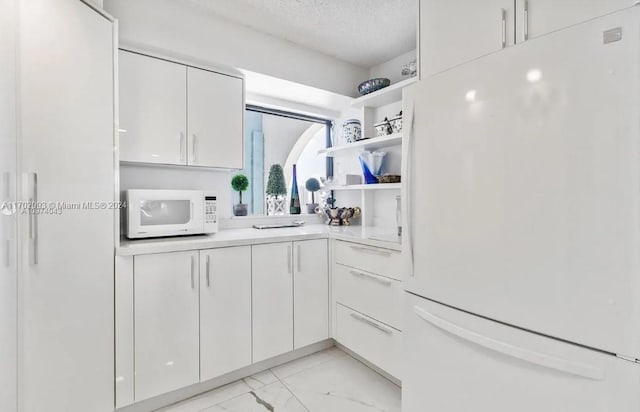 kitchen featuring a textured ceiling, white cabinetry, and white appliances