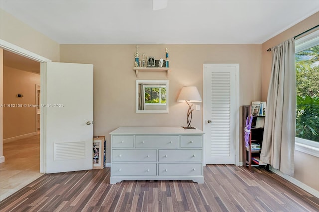 bedroom with baseboards, visible vents, and wood finished floors