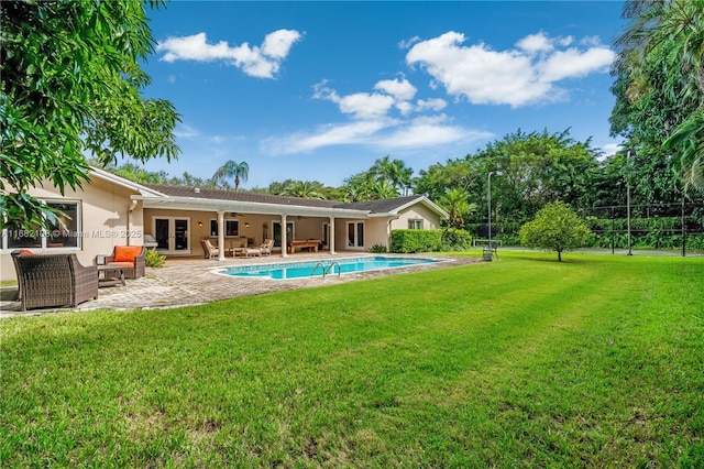 rear view of house featuring stucco siding, a lawn, fence, an outdoor pool, and an outdoor living space