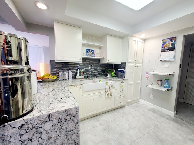 kitchen featuring light stone countertops, tasteful backsplash, white cabinets, and sink