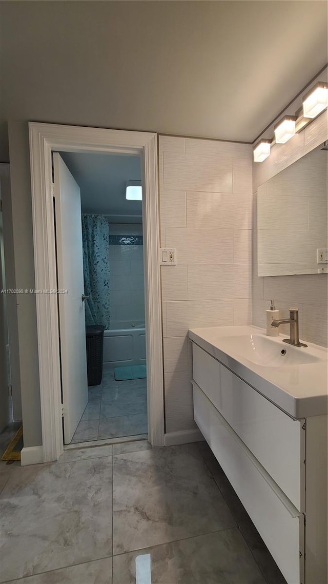 bathroom with vanity, shower / bath combo with shower curtain, and tile walls