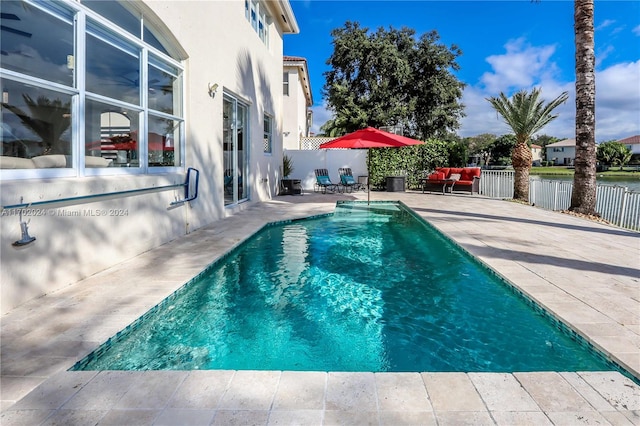 view of swimming pool with a patio, a water view, and an outdoor hangout area