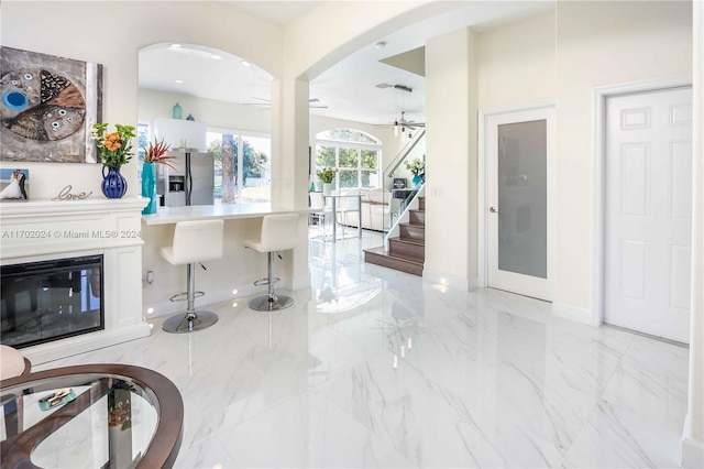 interior space with white cabinets, stainless steel fridge, ceiling fan, and a breakfast bar area