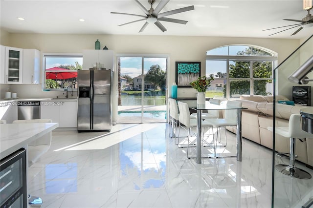 dining area featuring a wealth of natural light, sink, a water view, and beverage cooler