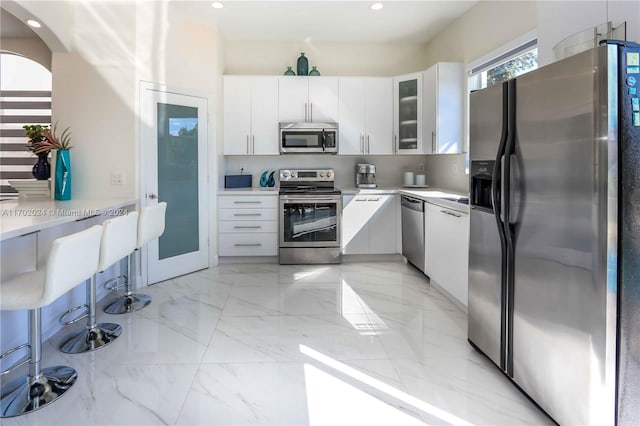 kitchen featuring appliances with stainless steel finishes, white cabinetry, and a kitchen breakfast bar