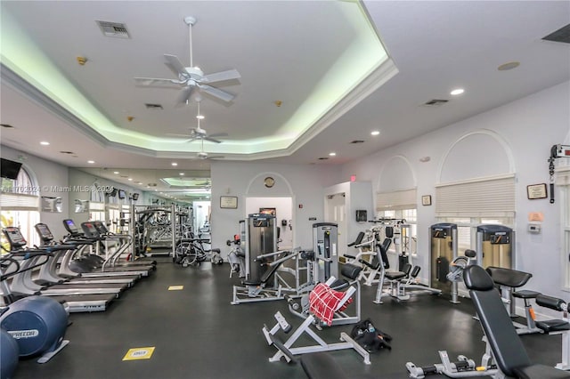 workout area with a raised ceiling and ceiling fan