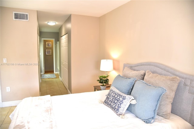 bedroom featuring a closet, visible vents, baseboards, and light tile patterned floors