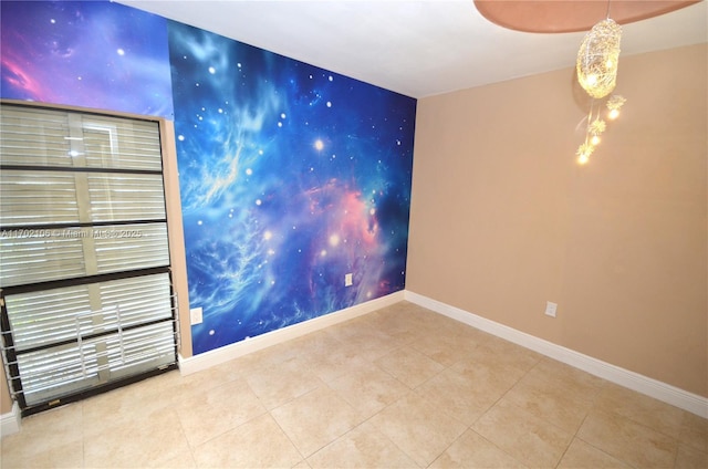 spare room with tile patterned flooring, an accent wall, and baseboards