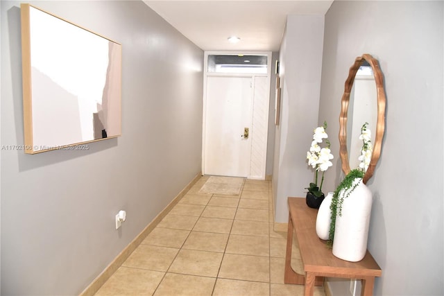 doorway featuring an AC wall unit, light tile patterned flooring, and baseboards