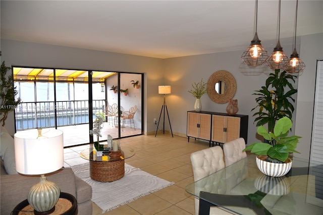 living room featuring light tile patterned flooring, a water view, and baseboards