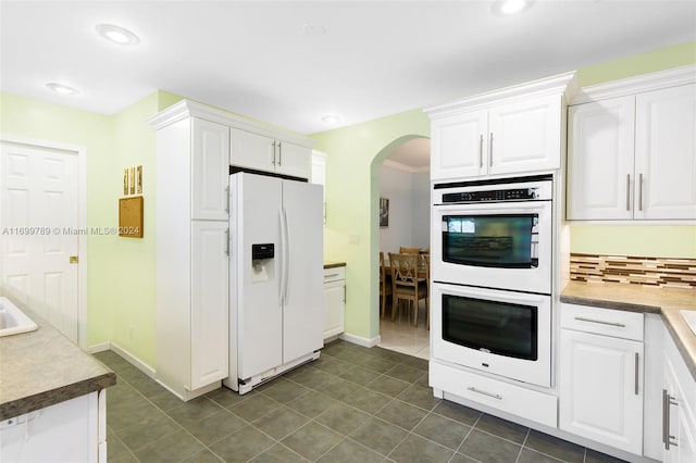 kitchen with white cabinetry, tasteful backsplash, white appliances, and dark tile patterned floors