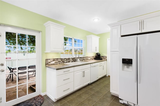 kitchen with sink, backsplash, white appliances, white cabinets, and dark tile patterned flooring