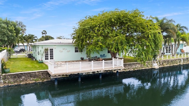 back of property featuring a deck with water view, french doors, and a yard