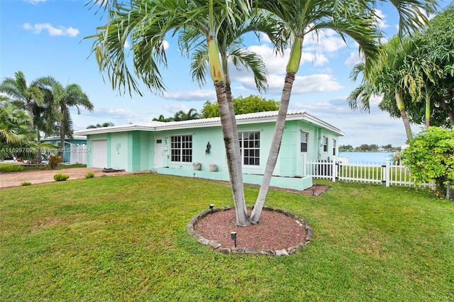 single story home featuring a garage, a water view, and a front lawn