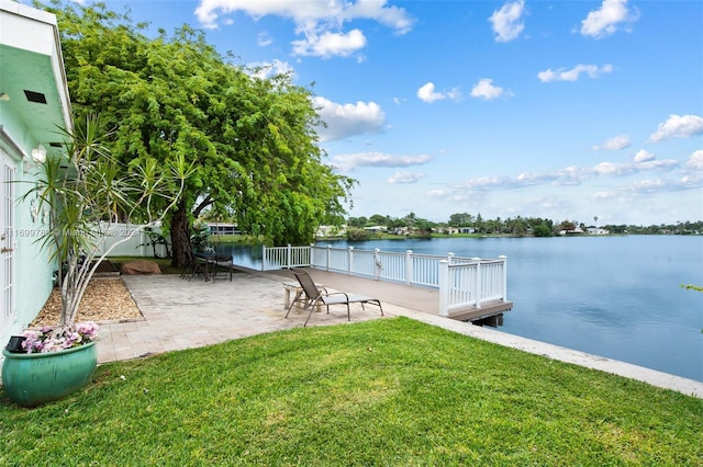 view of dock featuring a lawn, a water view, and a patio