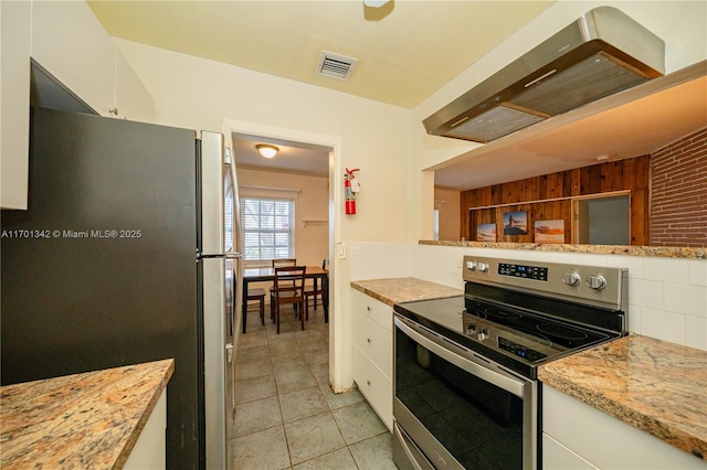 kitchen with appliances with stainless steel finishes, white cabinetry, backsplash, light tile patterned floors, and light stone countertops