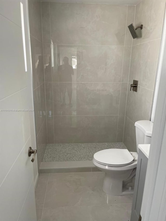 bathroom with tiled shower, vanity, and toilet