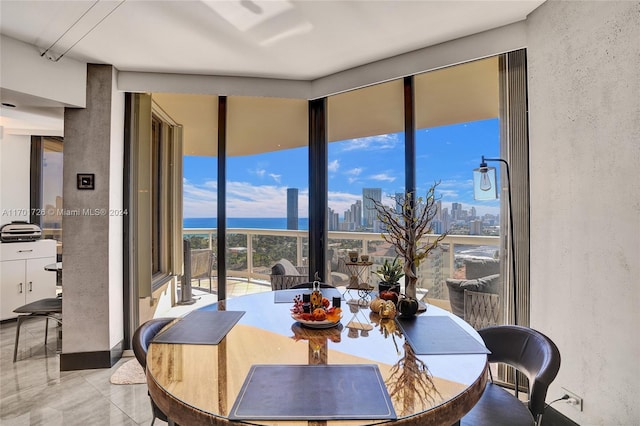 tiled dining space featuring a water view and a wall of windows