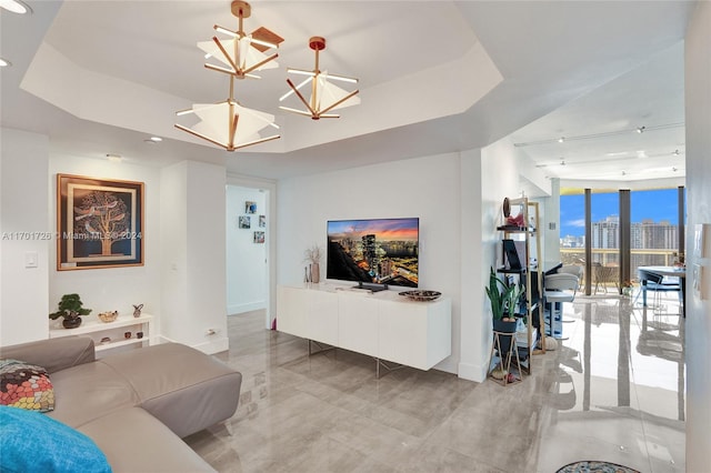 living room featuring a tray ceiling and an inviting chandelier