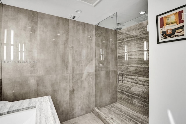 bathroom featuring a tile shower, vanity, and tile patterned floors