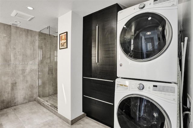 laundry area featuring light tile patterned floors and stacked washing maching and dryer