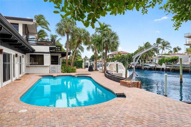 view of swimming pool with a dock, a patio, and a water view