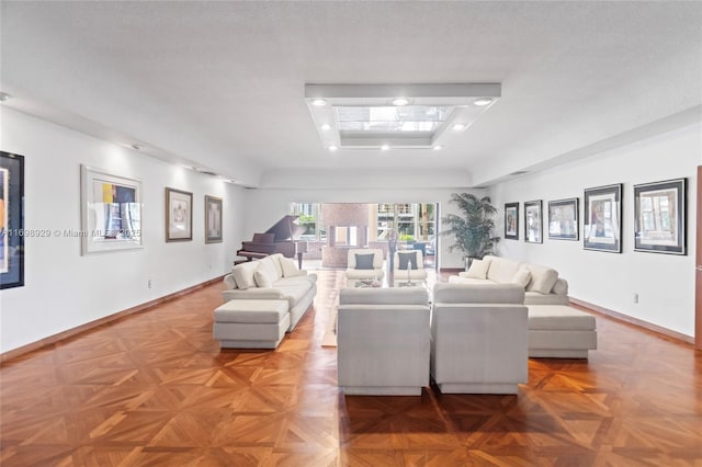 living room with light parquet floors, a textured ceiling, and a tray ceiling