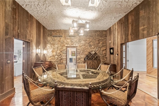 dining room with a chandelier, a textured ceiling, and wooden walls