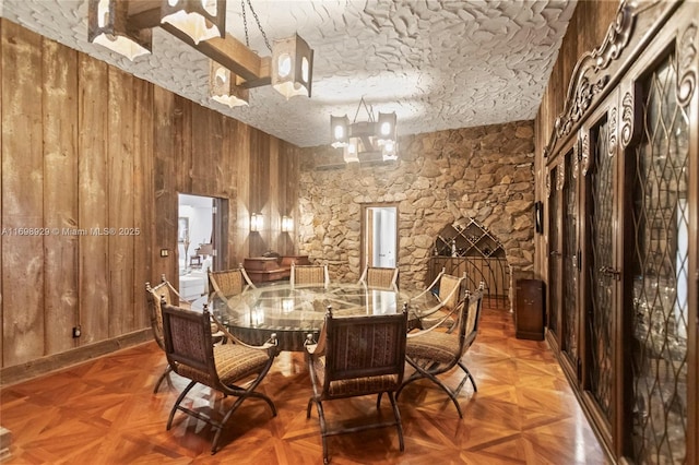 dining area with parquet flooring, a textured ceiling, and wood walls