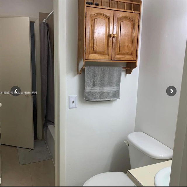 bathroom with tile patterned flooring, toilet, and shower / tub combo with curtain