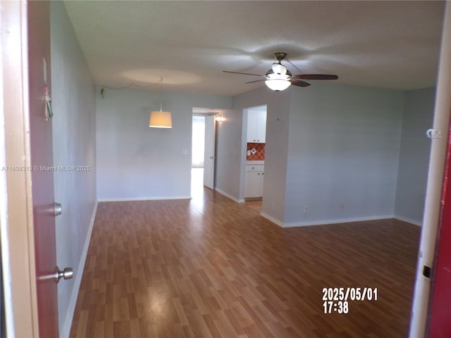 empty room featuring a ceiling fan, baseboards, and wood finished floors