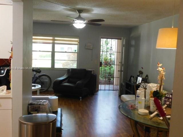 living room featuring wood-type flooring, a textured ceiling, and ceiling fan