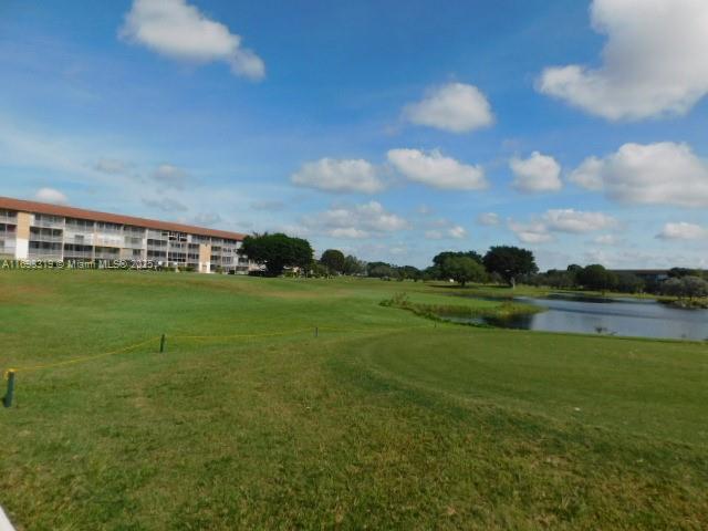 surrounding community featuring a lawn, a water view, and golf course view