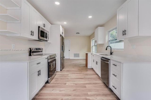 kitchen featuring white cabinets, appliances with stainless steel finishes, light wood-type flooring, and sink