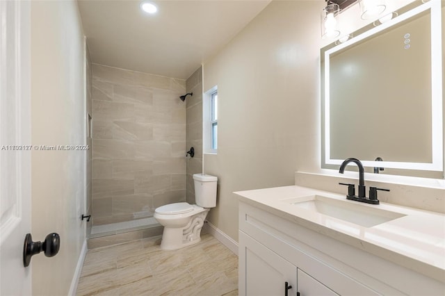 bathroom featuring a tile shower, vanity, and toilet