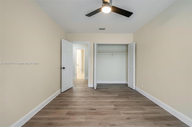 unfurnished bedroom featuring ceiling fan, a closet, and wood-type flooring