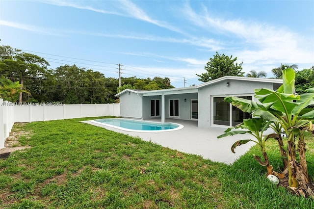 back of house featuring a fenced in pool, a patio area, and a lawn