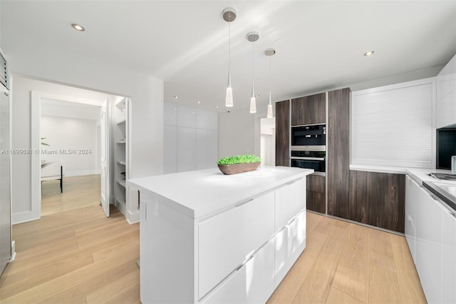 7155 Los Pinos Blvd, Coral Gables, FL 33143 - kitchen with double oven, a kitchen island, light hardwood / wood-style floors, and decorative light fixtures