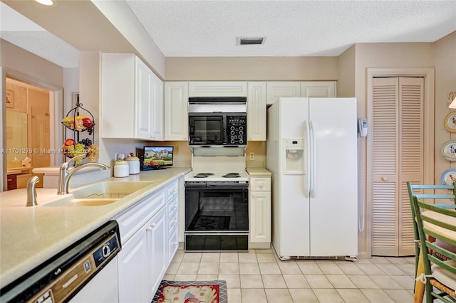 kitchen with a textured ceiling, white appliances, sink, white cabinets, and light tile patterned flooring