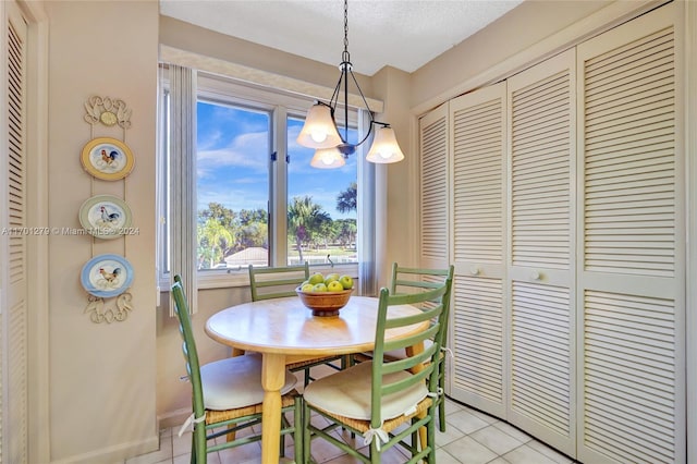 tiled dining room with a chandelier and a textured ceiling