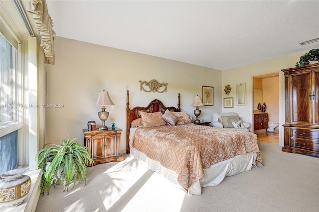 carpeted bedroom featuring a textured ceiling and ensuite bath