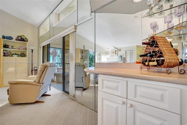 kitchen featuring light colored carpet, white cabinetry, and lofted ceiling