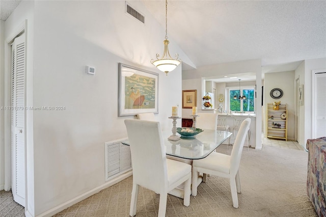 dining area with a textured ceiling and light colored carpet