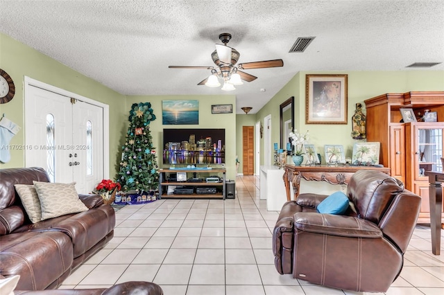 tiled living room with ceiling fan, a healthy amount of sunlight, and a textured ceiling